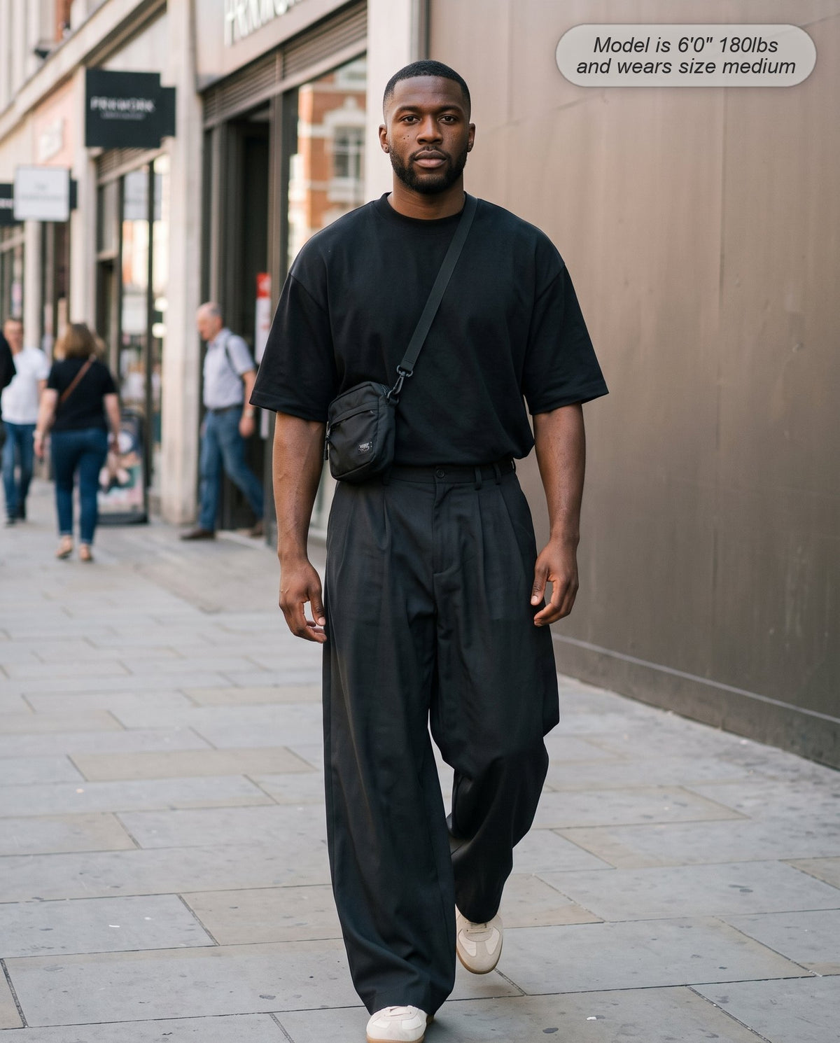 Man wearing the Envoy pleated wide leg trousers in black on a city street