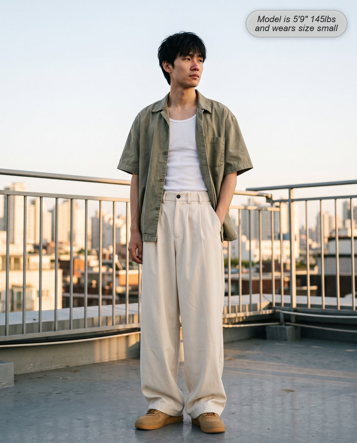 Man wearing the Envoy pleated wide leg trousers in cream on a rooftop