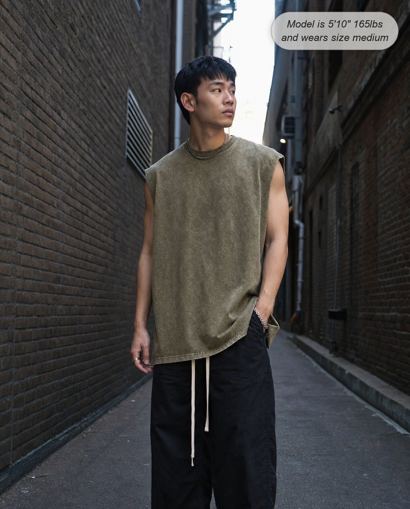 Man wearing the Ironclad acid wash tank in green in an alley