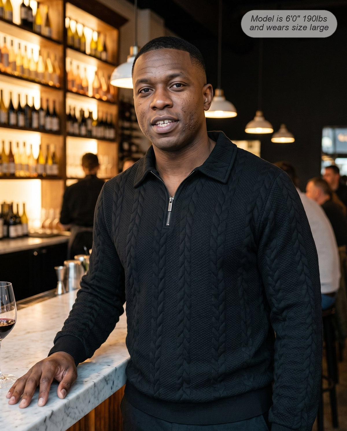 Man wearing the Regent quarter zip knit in black at a wine bar