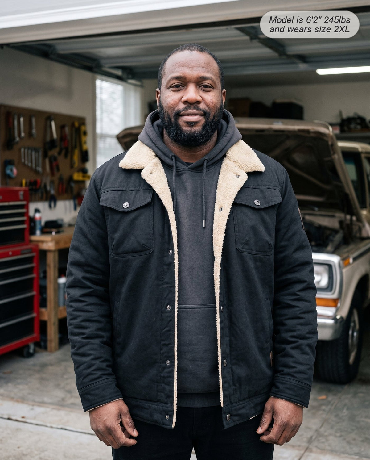 Man wearing the Sentinel sherpa jacket in black in a garage workshop