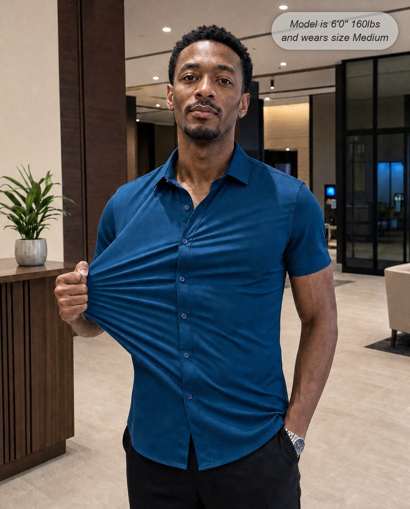 Sovereign stretch dress shirt in teal, short sleeve, stretching the fabric in a hotel lobby