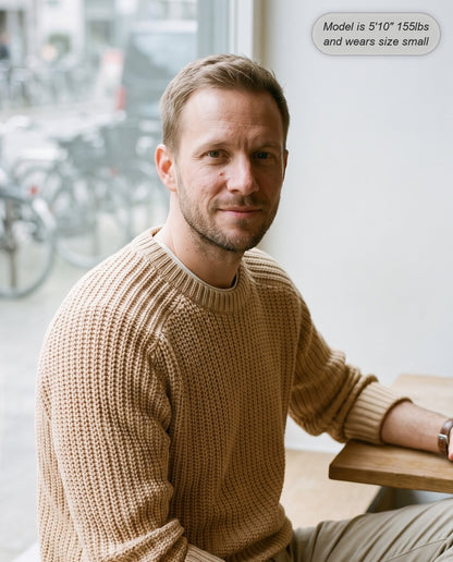 Man wearing the Admiral relaxed ribbed knit sweater in beige at a cafe window
