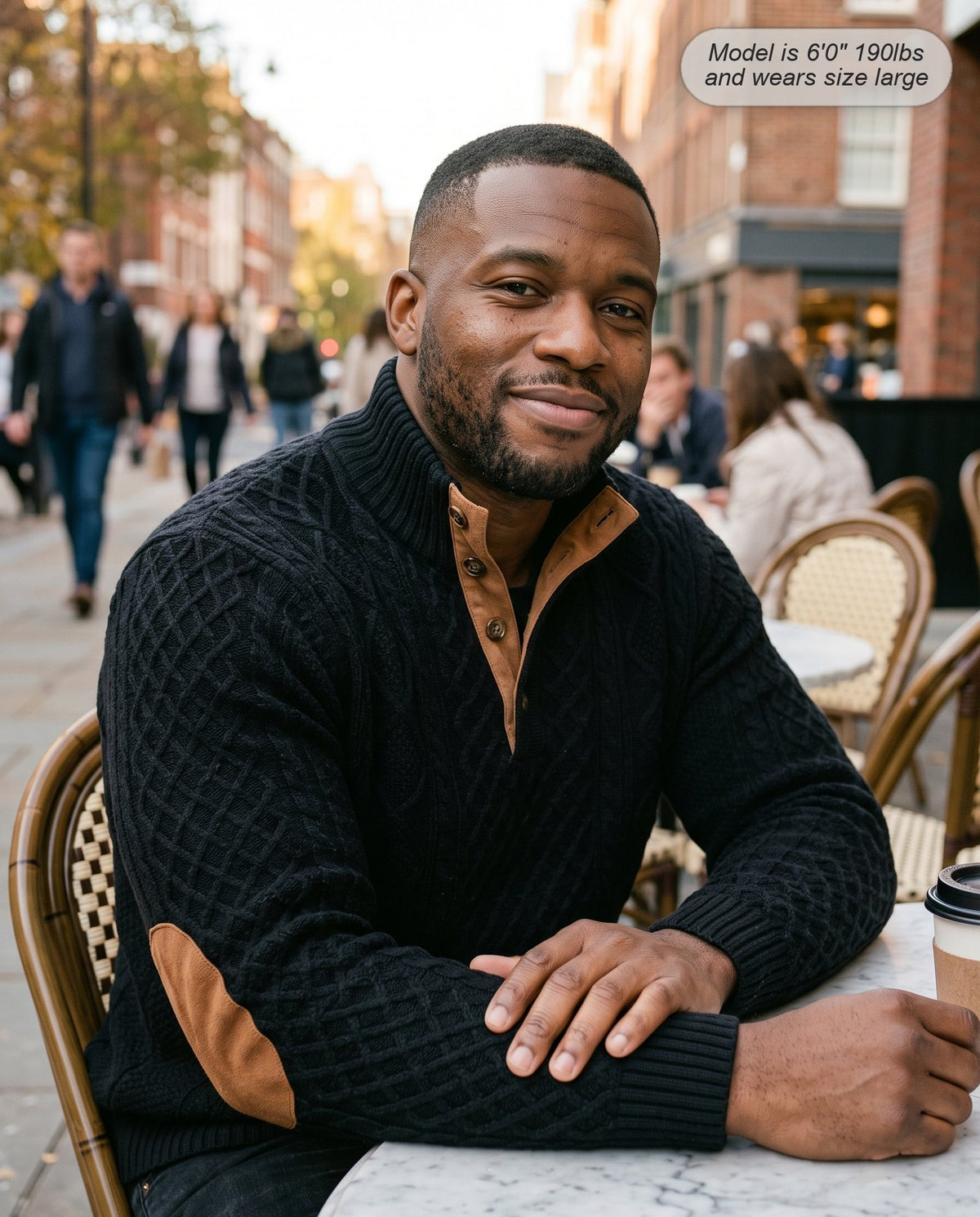 Man wearing the Warden jacquard sweater in black at a pavement cafe