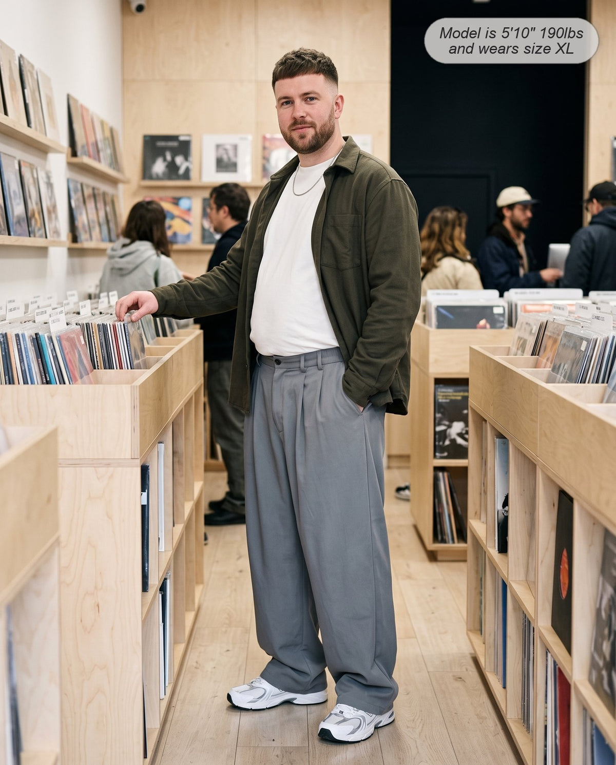Man wearing the Envoy pleated wide leg trousers in charcoal in a record shop