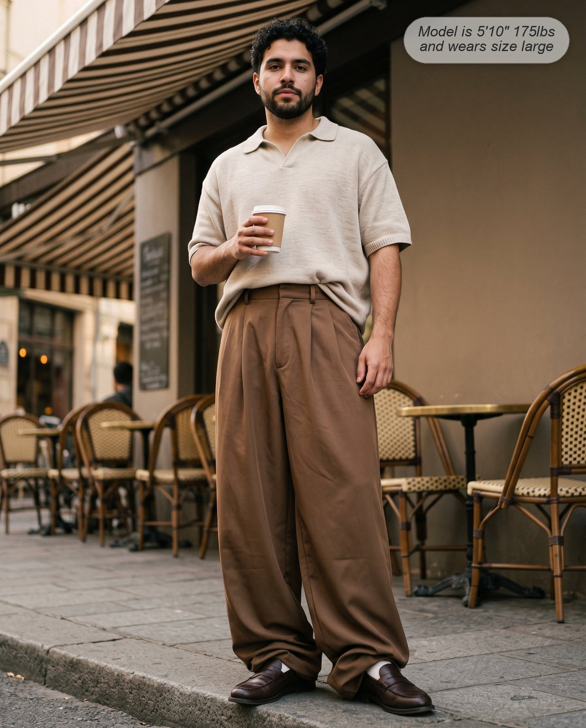 Man wearing the Envoy pleated wide leg trousers in coffee at a pavement cafe