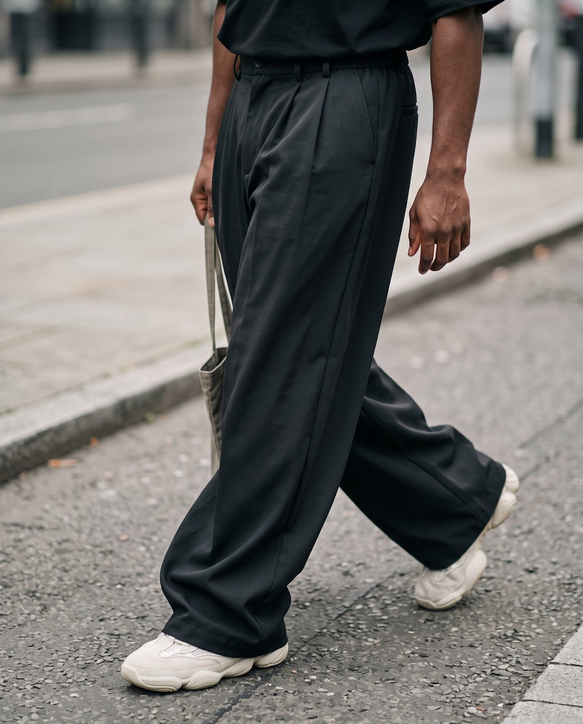 Close view of the wide leg and stacked hem of the Envoy trousers in black