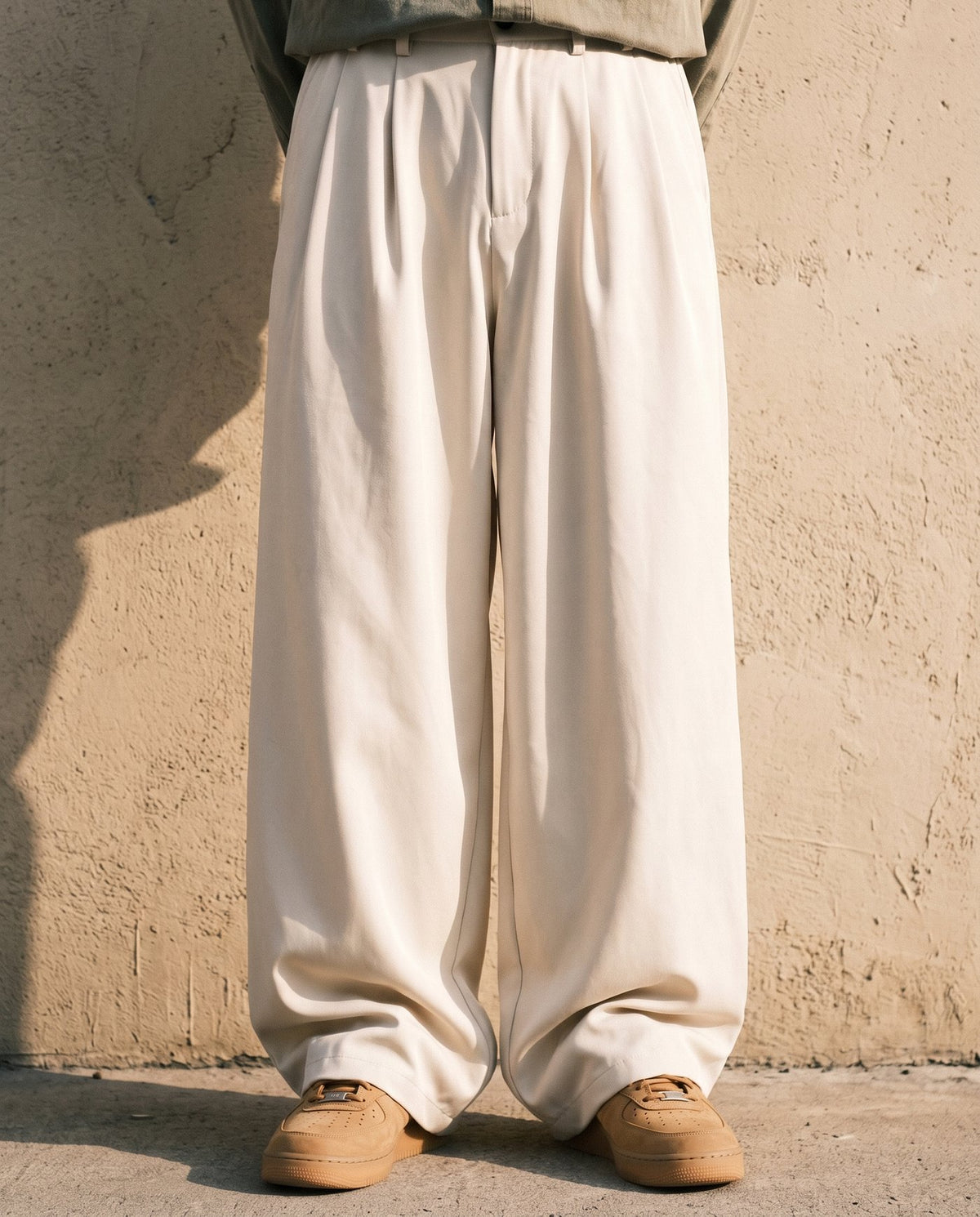 Full column of the Envoy trousers in cream against a plaster wall
