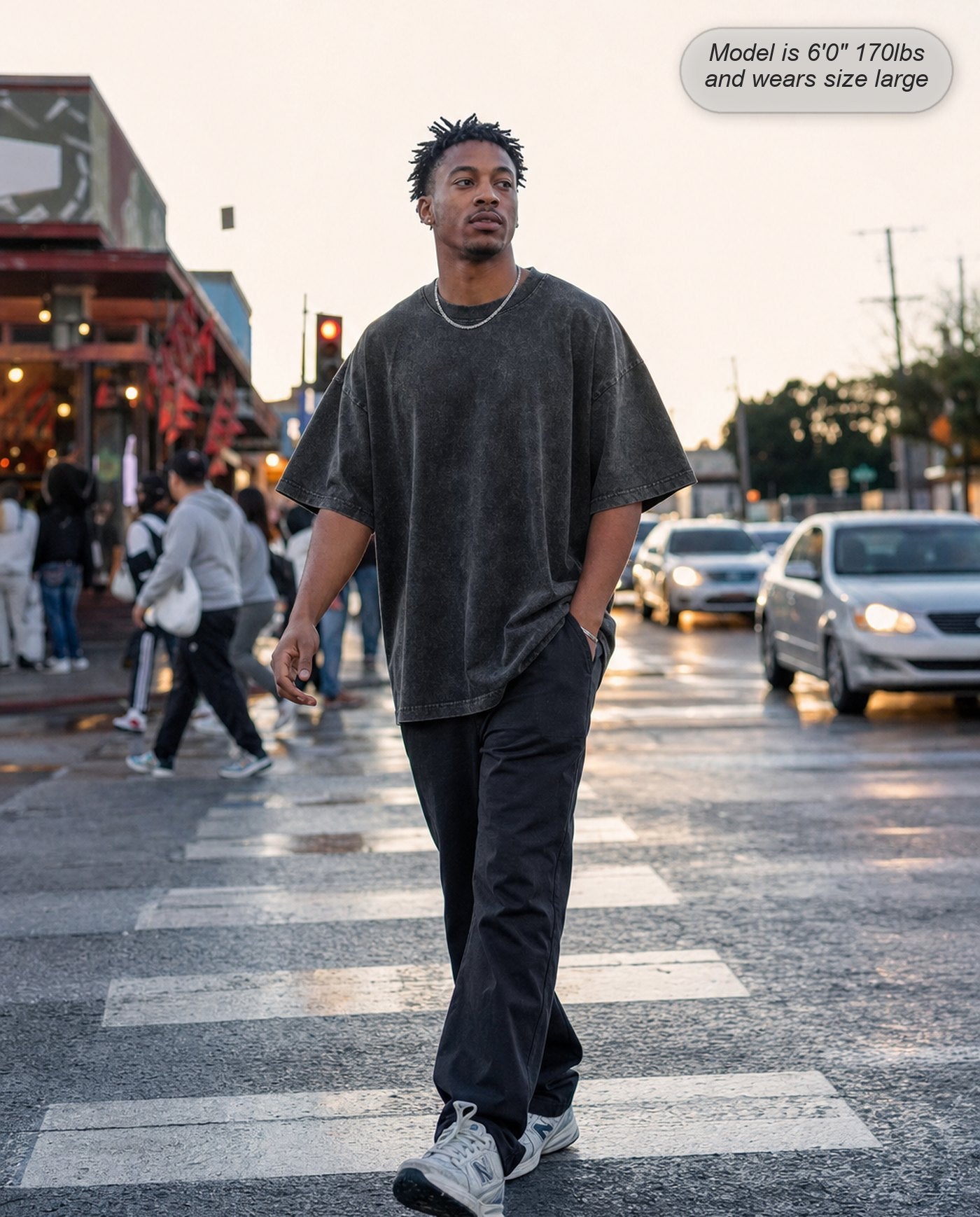 Man in a Washed Black Legion oversized acid wash tee crossing a city street at dusk