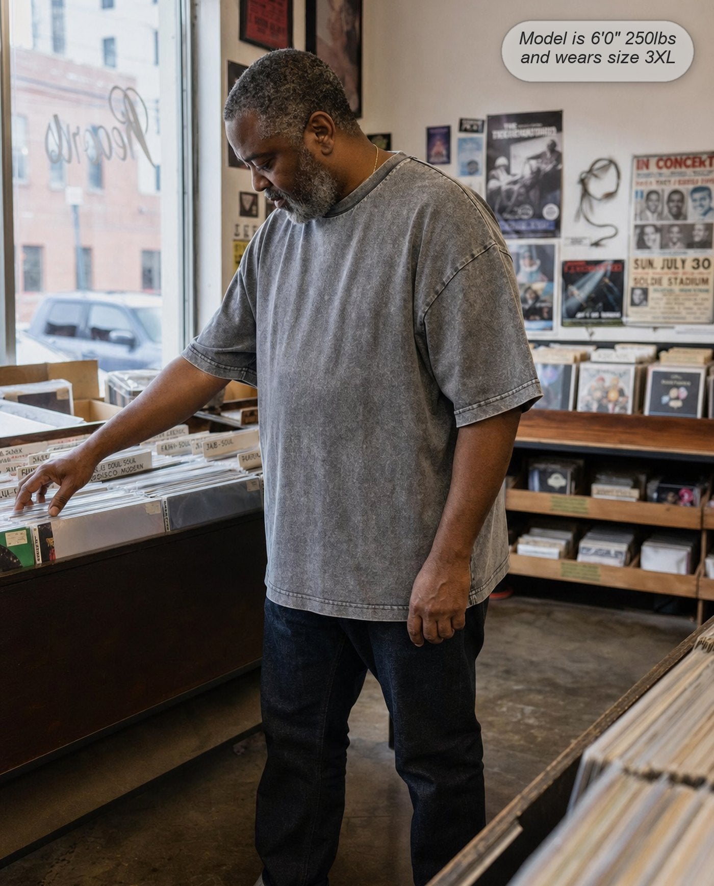 Man in a Stone Grey Legion oversized acid wash tee in a record shop