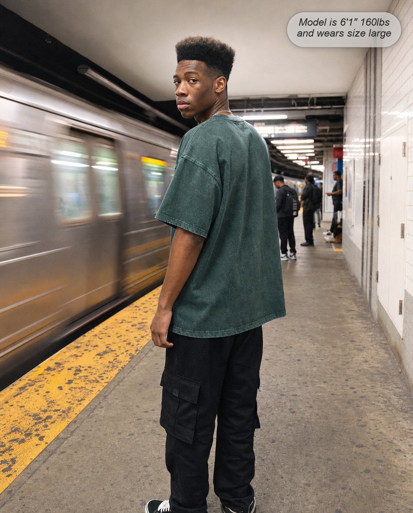 Man in a Forest Green Legion oversized acid wash tee on a subway platform