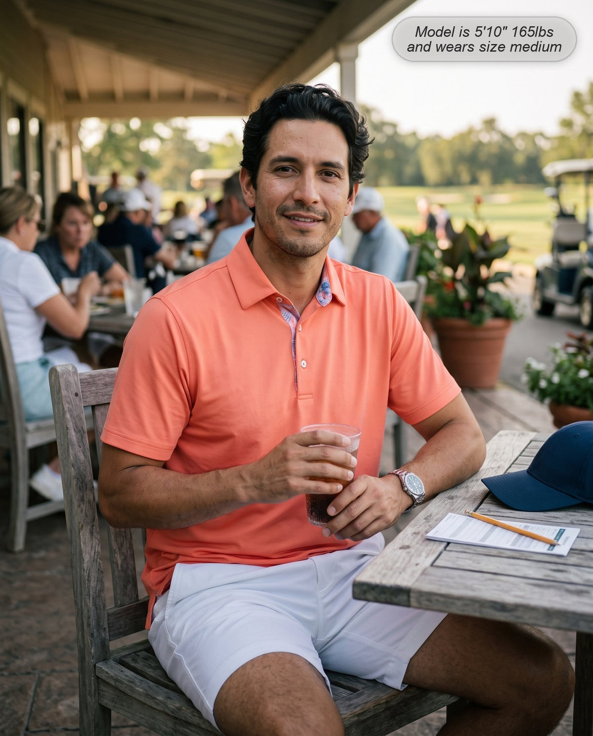 Man wearing the Meridian golf polo in coral on the clubhouse terrace