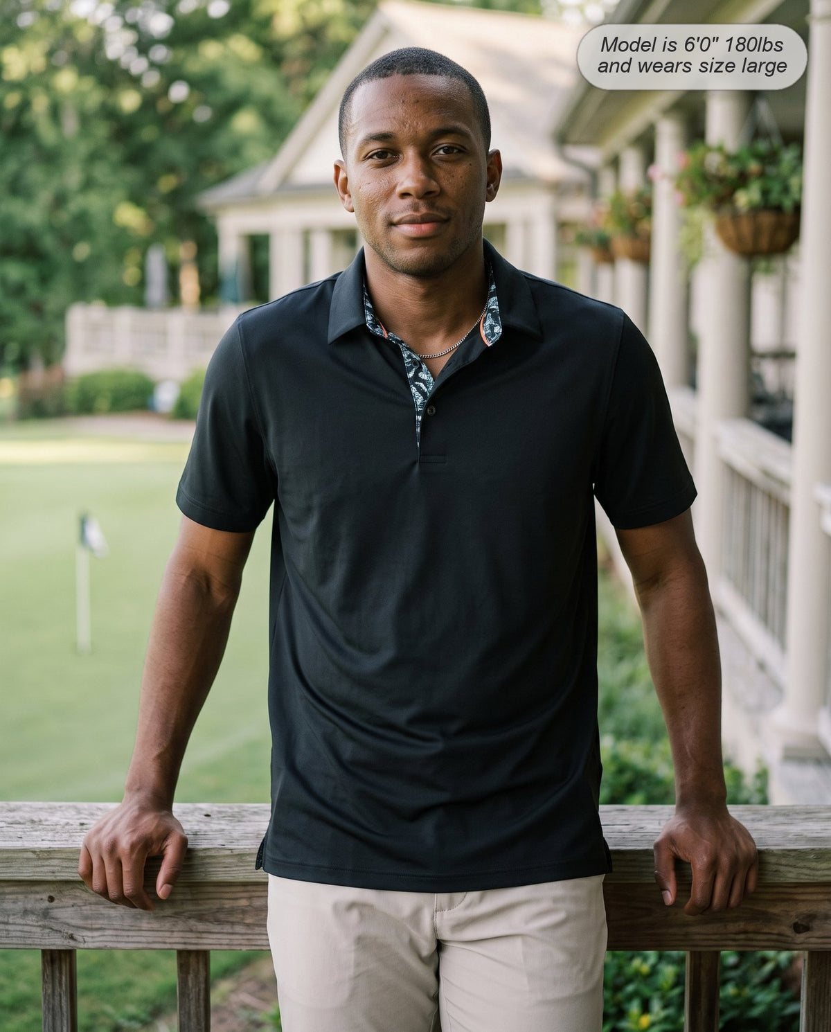 Man wearing the Meridian golf polo in black on the clubhouse veranda