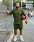 Man wearing the Monarch lounge short set in army green at a city basketball court