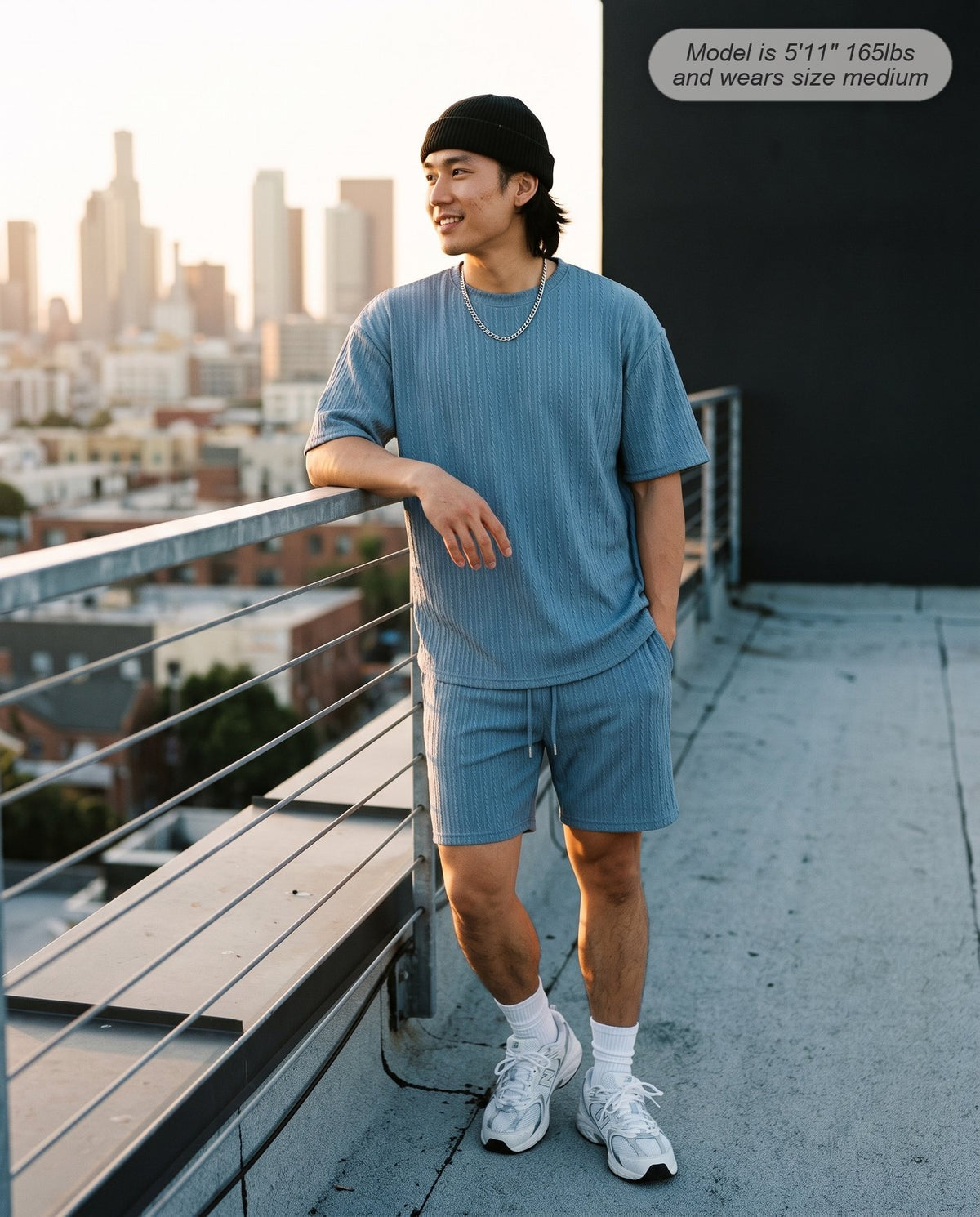 Man wearing the Monarch lounge short set in dusty blue on a rooftop at golden hour