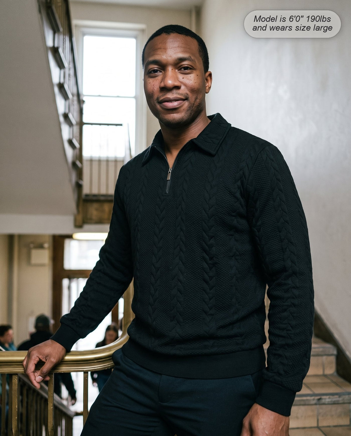 Man wearing the Regent quarter zip knit in black on a staircase
