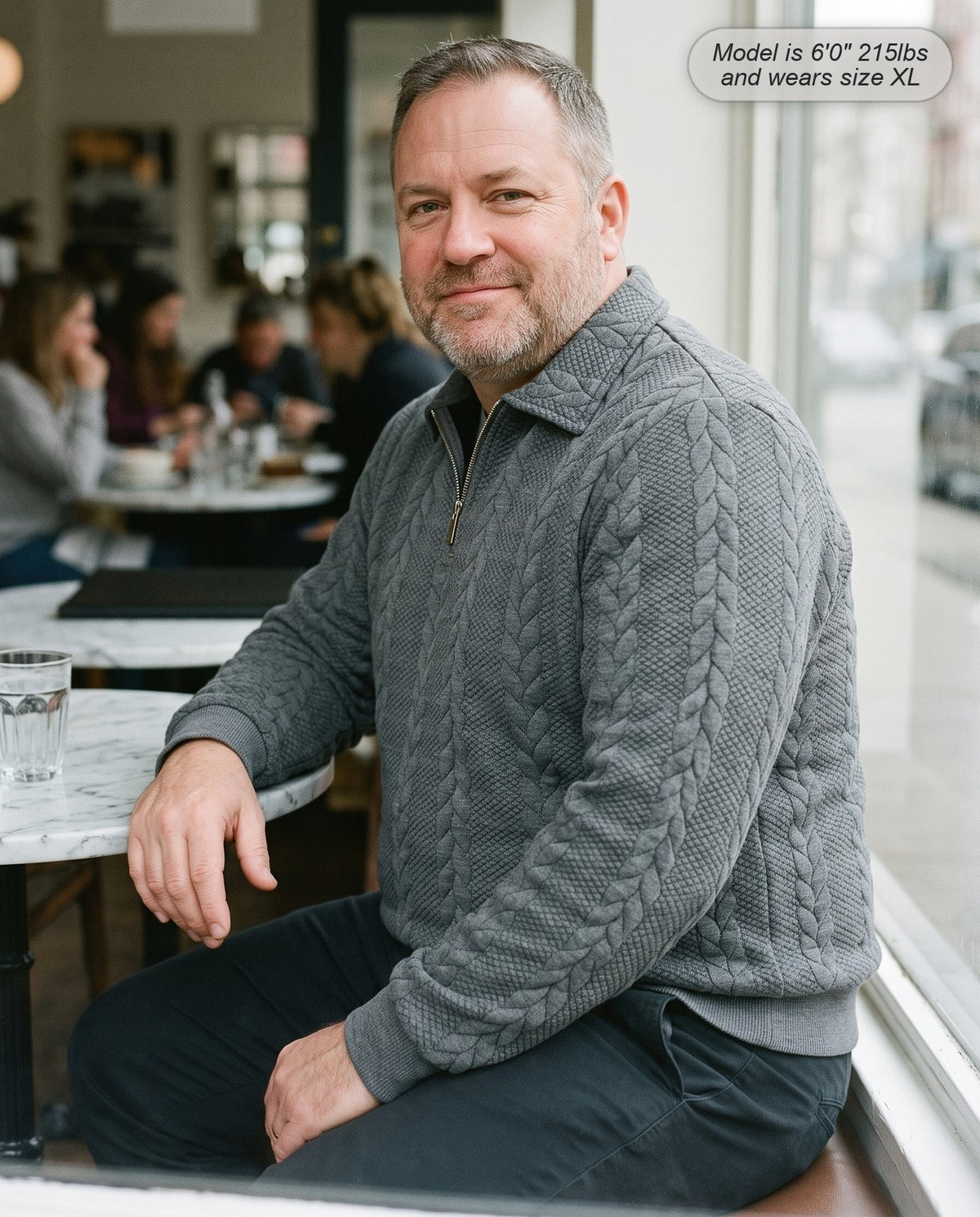 Man wearing the Regent quarter zip knit in heather grey in a cafe window